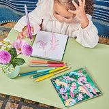 Child coloring with crayons on a table with coloring books and flowers.