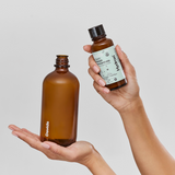 Two brown bottles, one labeled 'Davids' and the other 'Hydrol,' held by a person against a light background.