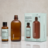 Brown mouthwash bottles and packaging on a reflective surface with a neutral background