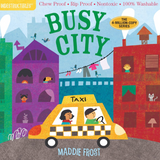Children's board book cover titled 'BUSY CITY' by Maddie Frost, showing a colorful illustrated city scene with tall purple, red, and blue buildings, a yellow taxi, and children in the streets. The top banner reads 'Indestructibles' and includes product feature callouts.