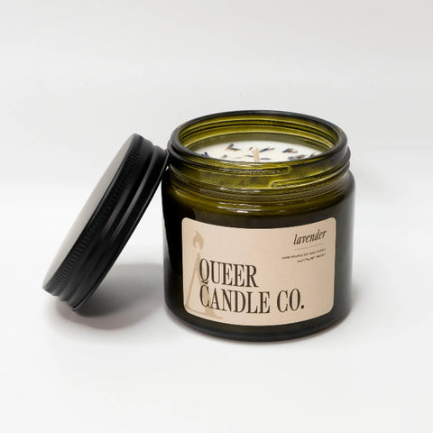Candle jar with lid open, displaying 'Queer Candle Co.' label on a white background