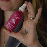 Person holding a 'Lovewild' rose dew bottle over their hand.