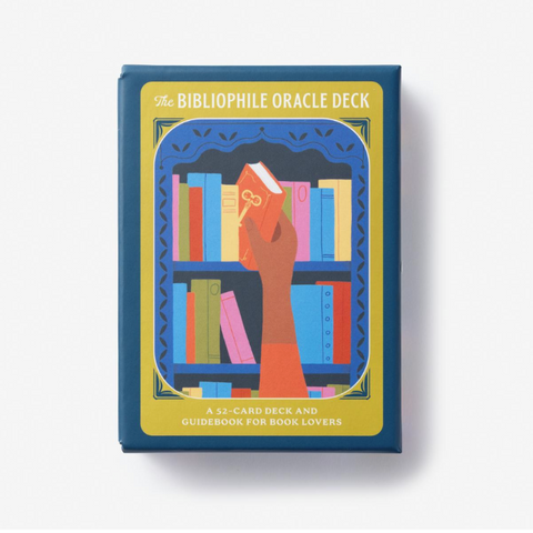 The Bibliophile Oracle Deck box on a clean white background. The box features a dark blue border with a central yellow illustration of a hand holding a book in front of bookshelves.