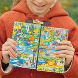 Child holding colorful children's books with animal illustrations in an outdoor setting